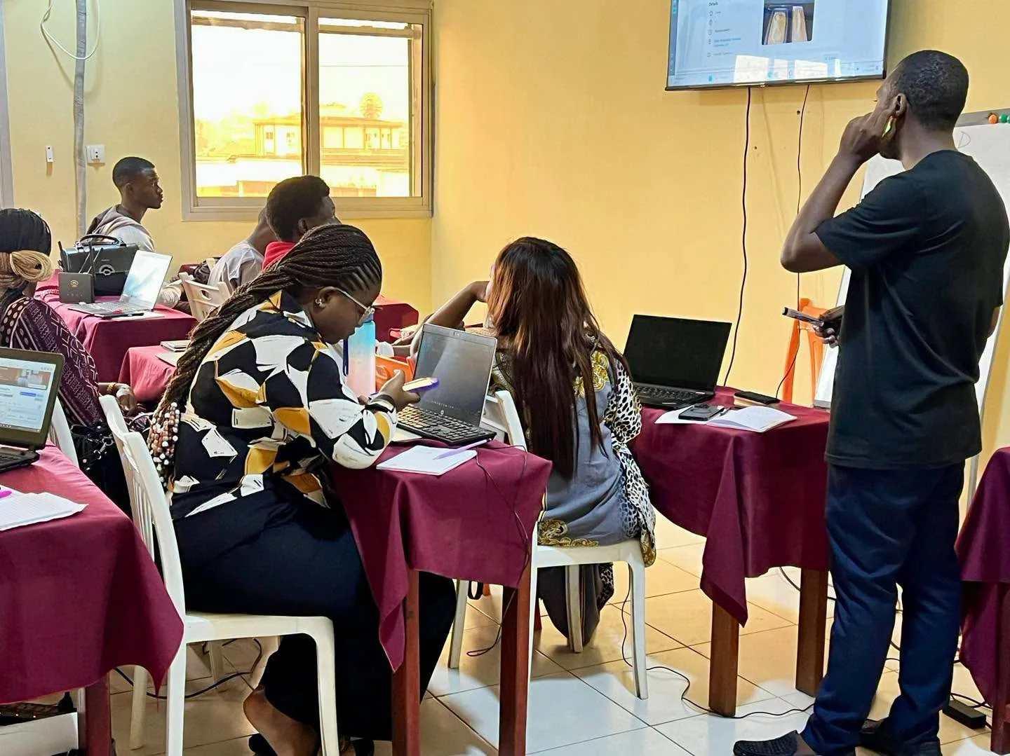 Session de formation en salle informatique : apprenants sur leurs ordinateurs portables et formateur devant l'écran