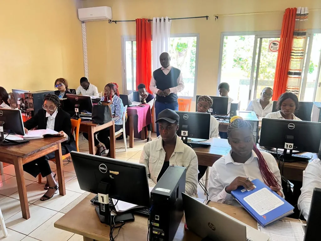 Apprenantes en travaux pratiques devant des postes informatiques, avec leur formateur
