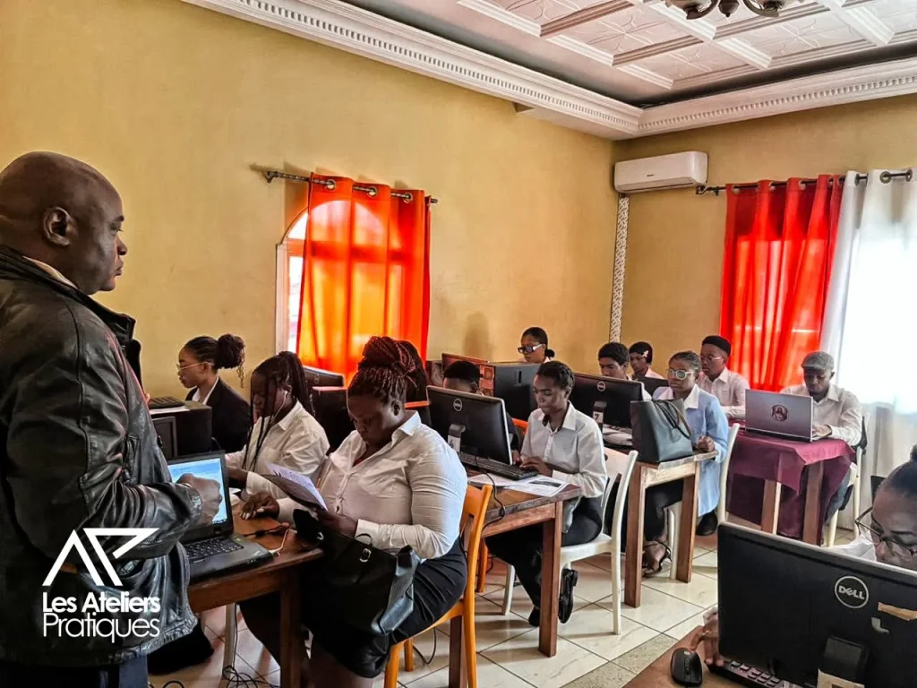 Un formateur s'adresse à un groupe d'apprenants en salle informatique