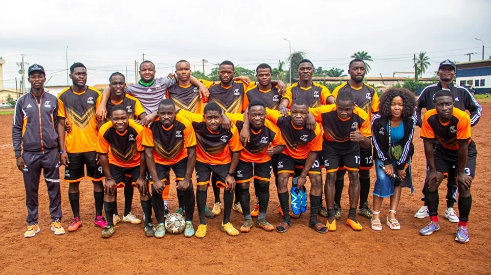 L'équipe de football des Ateliers Pratiques sur le terrain, en maillot orange et noir
